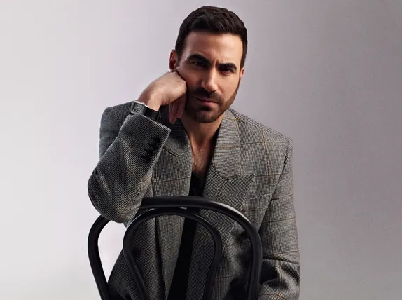 Brett Goldstein seated resting his hand on his face