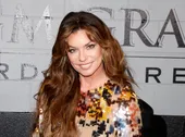 Shania Twain with curly hair in a sparkly dress at an event